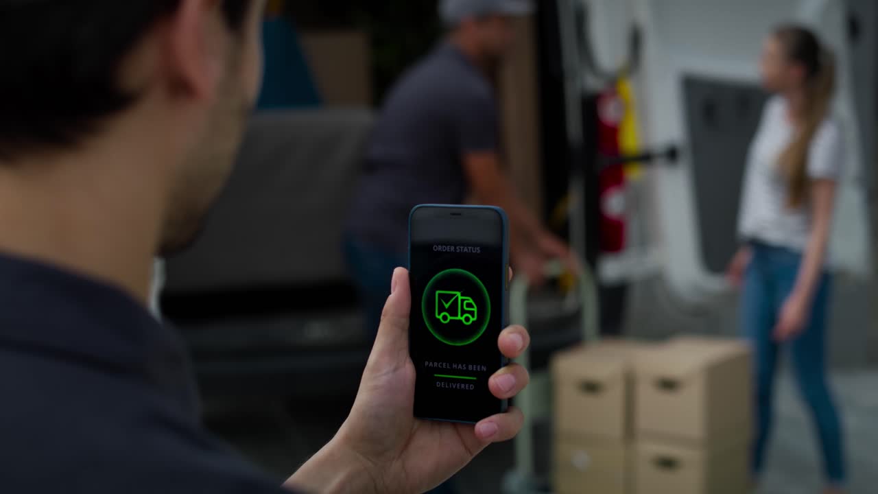 Rear view of delivery man holding phone with mobile app