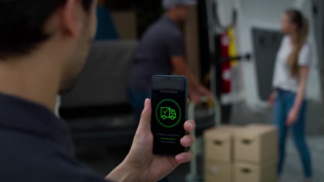 vista trasera del hombre de la entrega sosteniendo el teléfono con aplicación móvil
