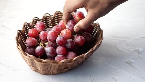 recogiendo a mano uvas rojas de una canasta de mimbre