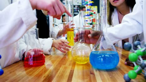 Mid-section-of-schoolkids-experimenting-chemical-in-laboratory-4k