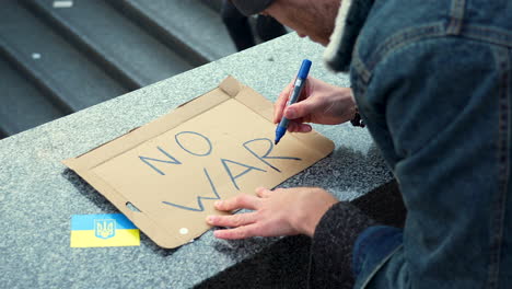 man preparing a cardboard sign to protest against war in ukraine, slow