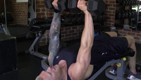 muscly man in home gym exercising decline dumbbell chest press