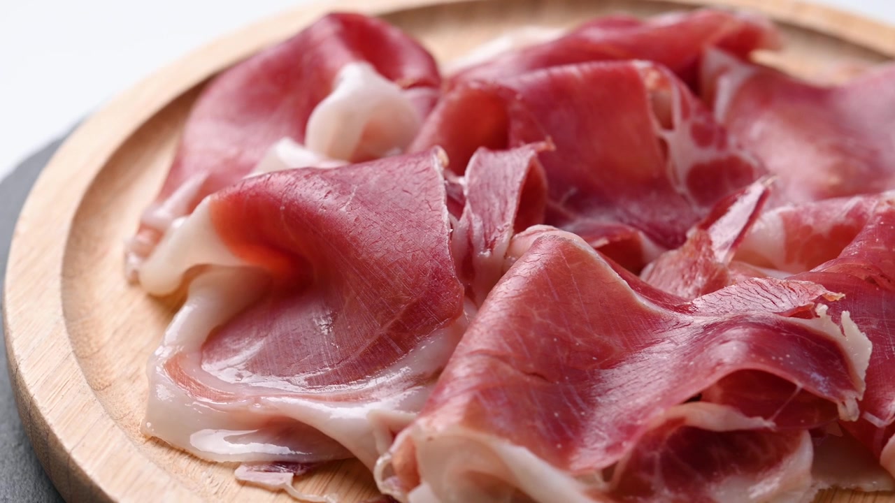 Prosciutto affettato sottilmente su un piatto di legno