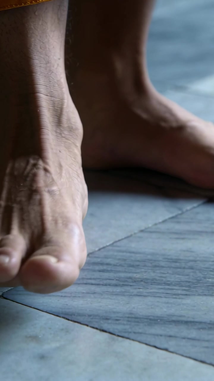 Video verticale: Uno spostamento di peso fa flettere e rotolare i piedi sulle piastrelle per l'equilibrio, con un orlo giallo.