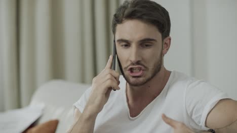 unhappy man talking mobile phone at home. angry person scream at phone