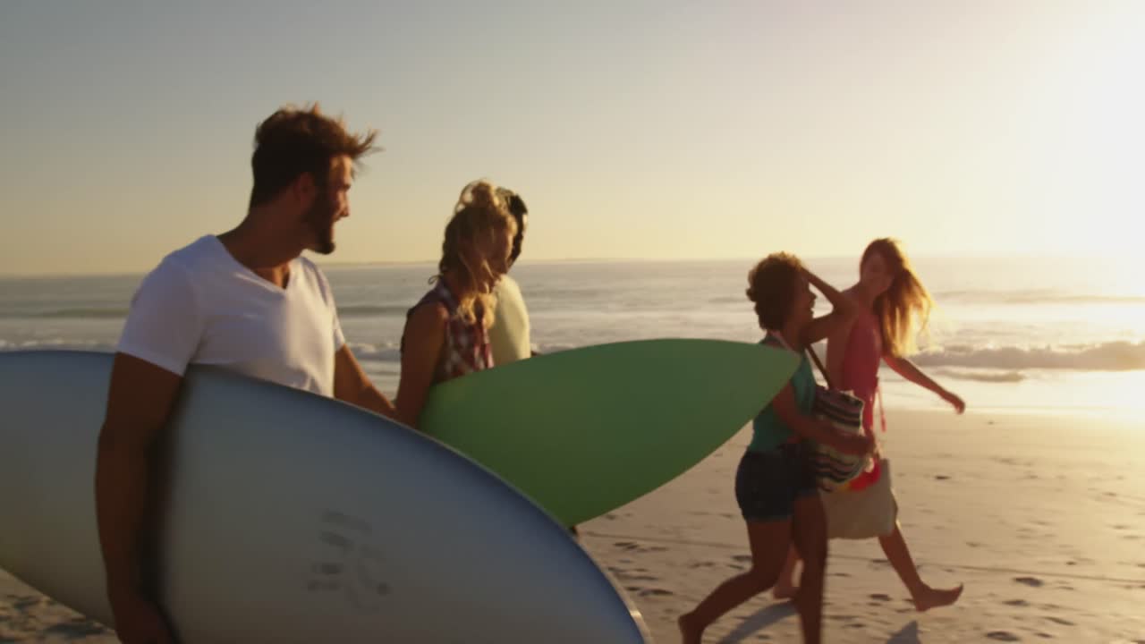 Amici giovani che passeggiano in spiaggia al tramonto 4k