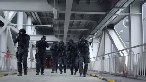 grupo swat con rifles moviéndose en el puente. fuerzas especiales de la policía mirando a su alrededor