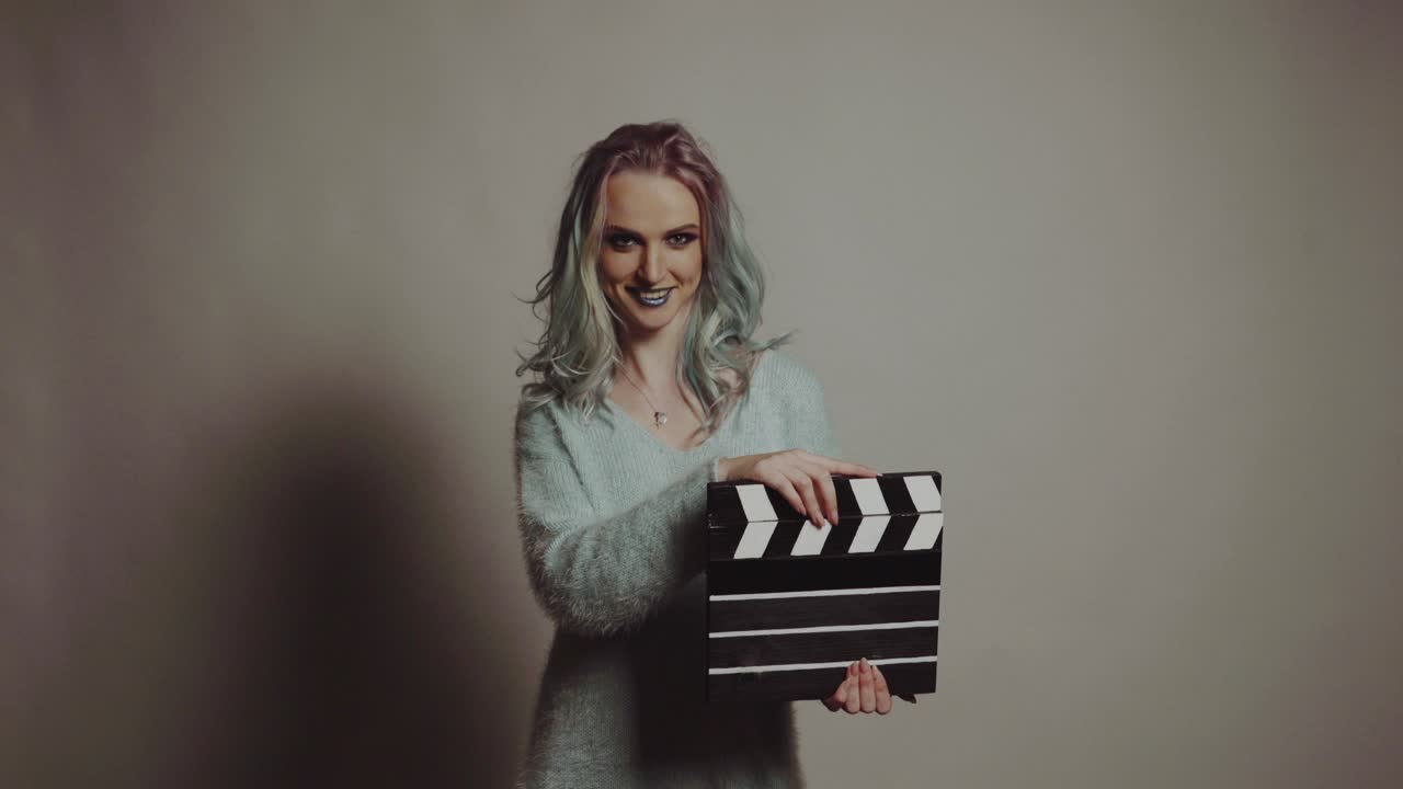 Film production and movie making concept. Portrait of young pretty woman with clapperboard.