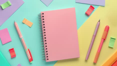 colorful stationery arrangement with notebooks and pens on colorful background