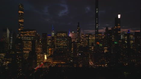 Slider-of-tall-downtown-skyscrapers-against-twilight-sky.-Night-city-scene.-Illuminated-high-rise-buildings-and-streets.-Manhattan,-New-York-City,-USA