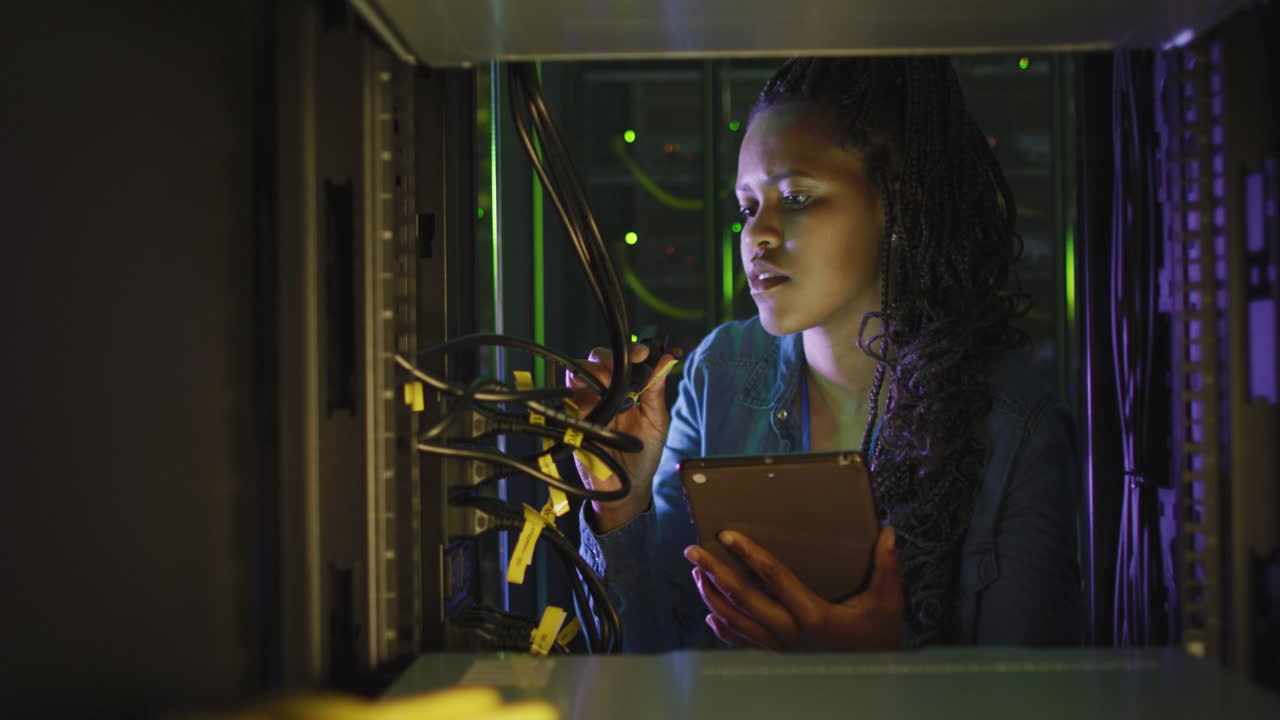 African american female computer technician using tablet working in business server room