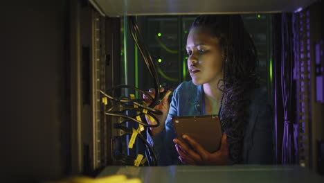 técnica informática afroamericana que usa una tableta trabajando en una sala de servidores de negocios