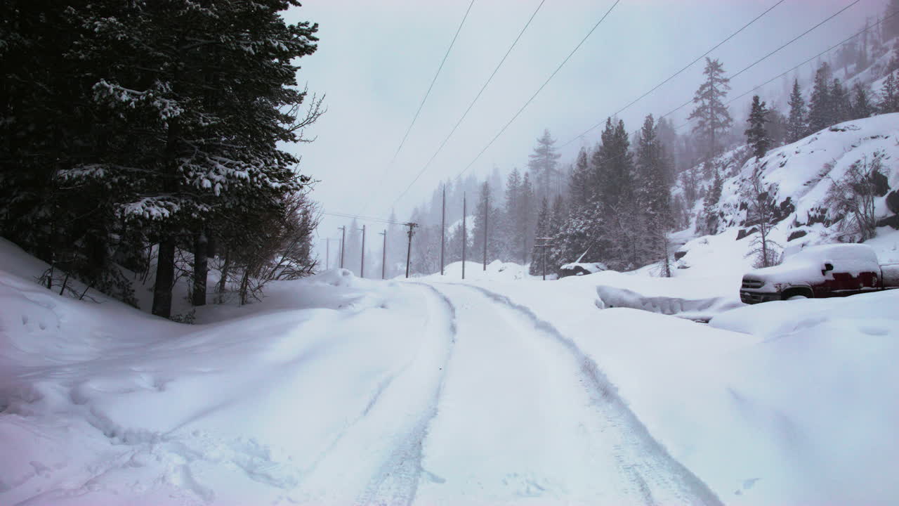 차량 트랙이 보이는 도로에 눈이 내립니다.