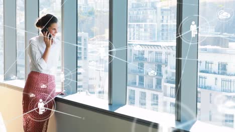 Animation-Verbundener-Cloud--Und-Personensymbole-über-Einer-Lächelnden-Geschäftsfrau,-Die-Im-Büro-Telefoniert