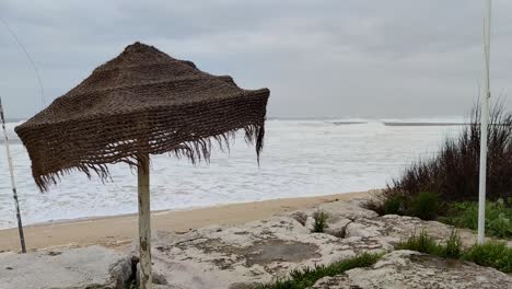 olas de tormenta en la orilla de la playa, sombrero de playa de paja ondeando con fuertes vientos