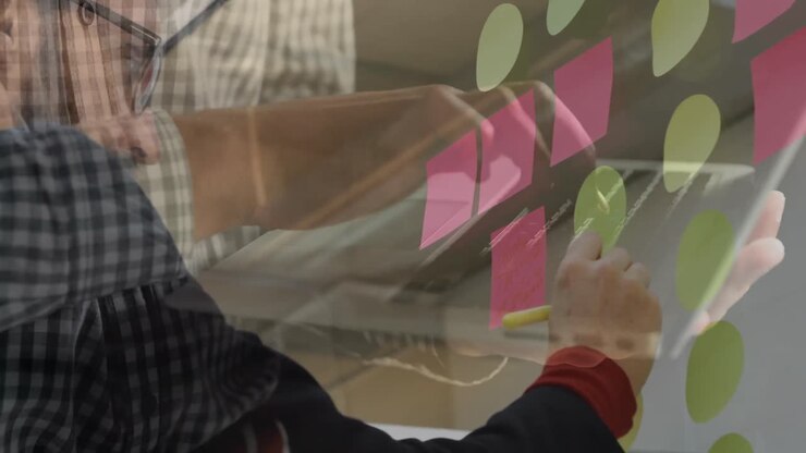 Animation of hands working on laptop over brainstorming businessman writing notes in office