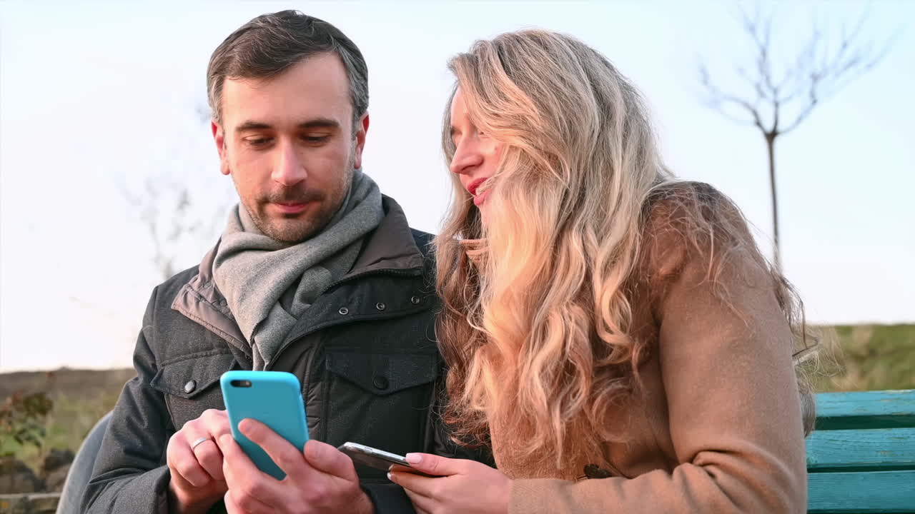 Young man shows to a smiling woman something in the phone