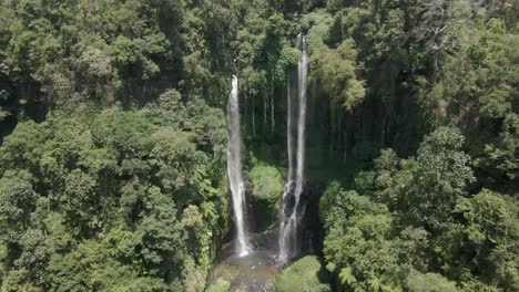 aerial approaches sekumpul waterfall flowing out of jungle cliff, bali