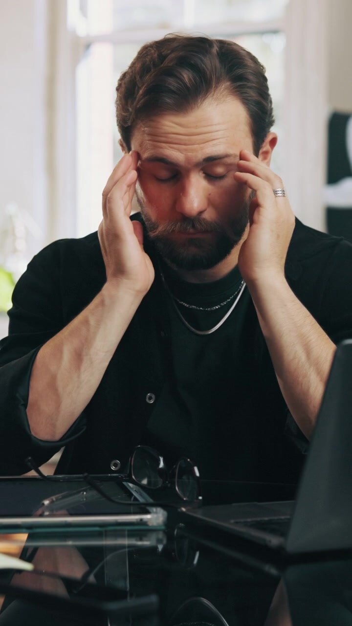 Uomo stressato che si toglie gli occhiali mentre lavora alla scrivania