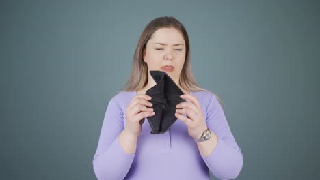 penniless young woman looking at her empty wallet.