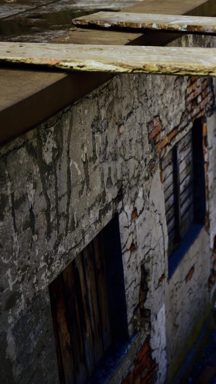 Vecchio muro con finestre che mostrano segni di usura in un'area urbana al tramonto