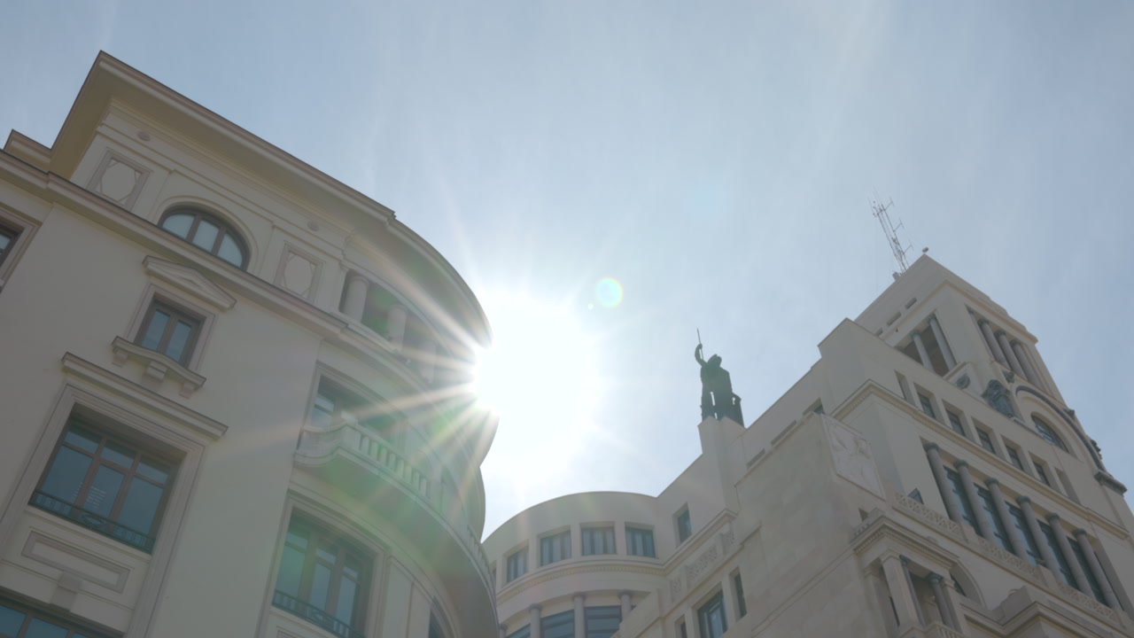 Sunlit Historic Facades And Statue Silhouette Under Clear Blue Sky, Lowangle Upward Pan, Strong Sun Flare