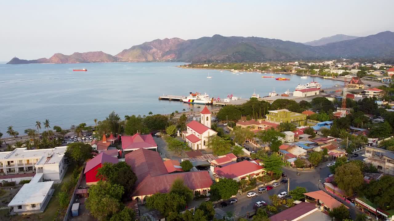 도시 건물, 도로, 교통, 크리스토 레이 동상 및 바다의 전망과 함께 동남아시아의 티모르-레스테의 수도  ⁇ 리 위로 떠오르는 공중 드론 뷰