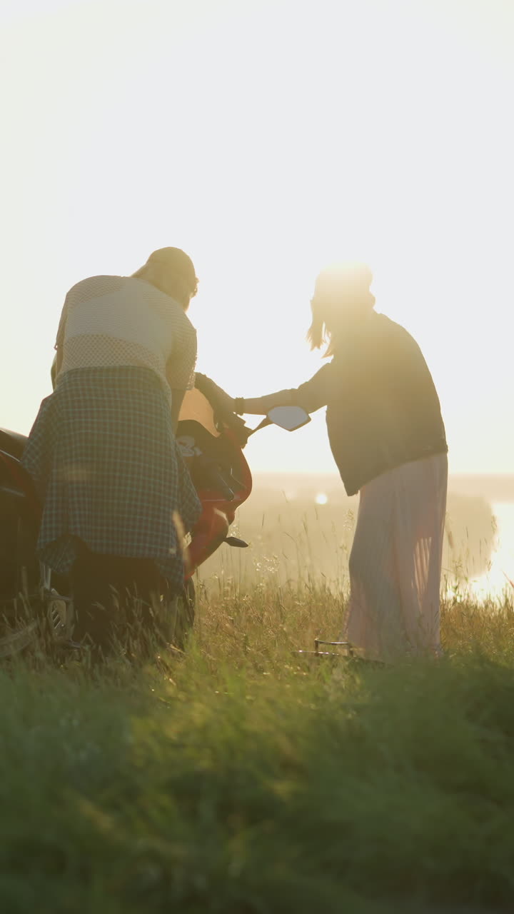 두 자매는 뒷면에 흐릿한 멀리 떨어진 물체의 아름다운 전망과 함께 열린 잔디에서 은 전력 자전거를 조심스럽게 청소하는 데 집중했습니다.