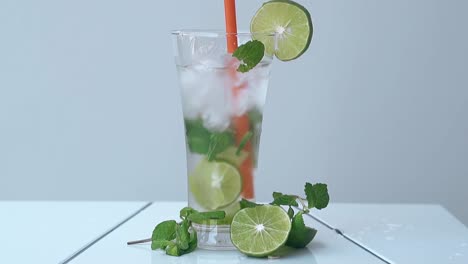 une paille orange remue un mojito froid dans un grand verre étincelant.