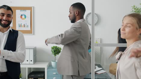 playful afro-american businessman dancing with employees in office having fun