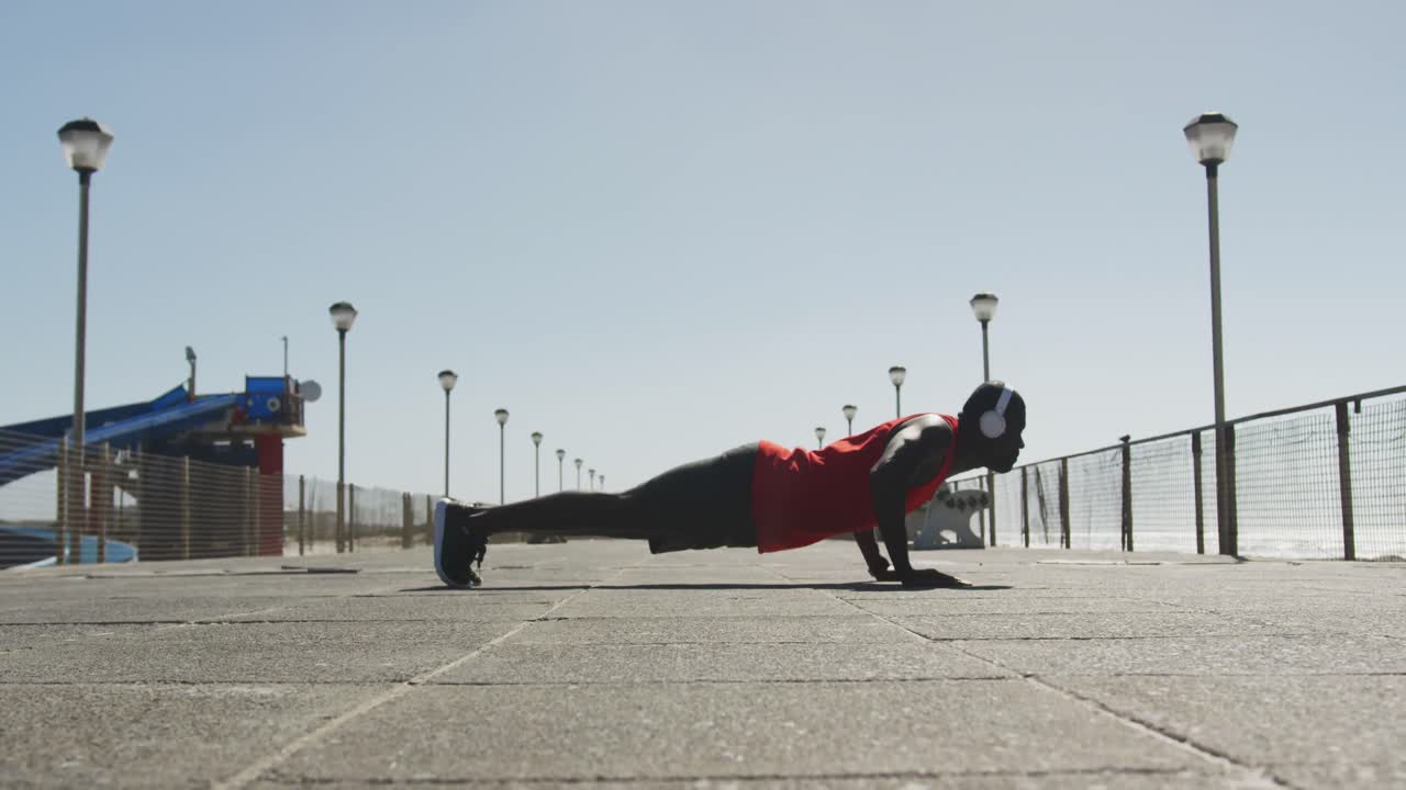 hombre afroamericano enfocado haciendo abdominales, haciendo ejercicio al aire libre a orillas del mar
