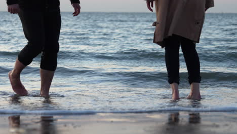 feet of a romantic couple enjoying the beach during sunset