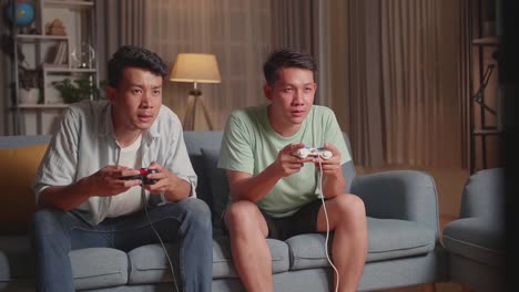 asian friends playing video games at home. one win and one lost