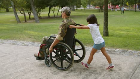 daughter kid wheeling wheelchair with disabled dad