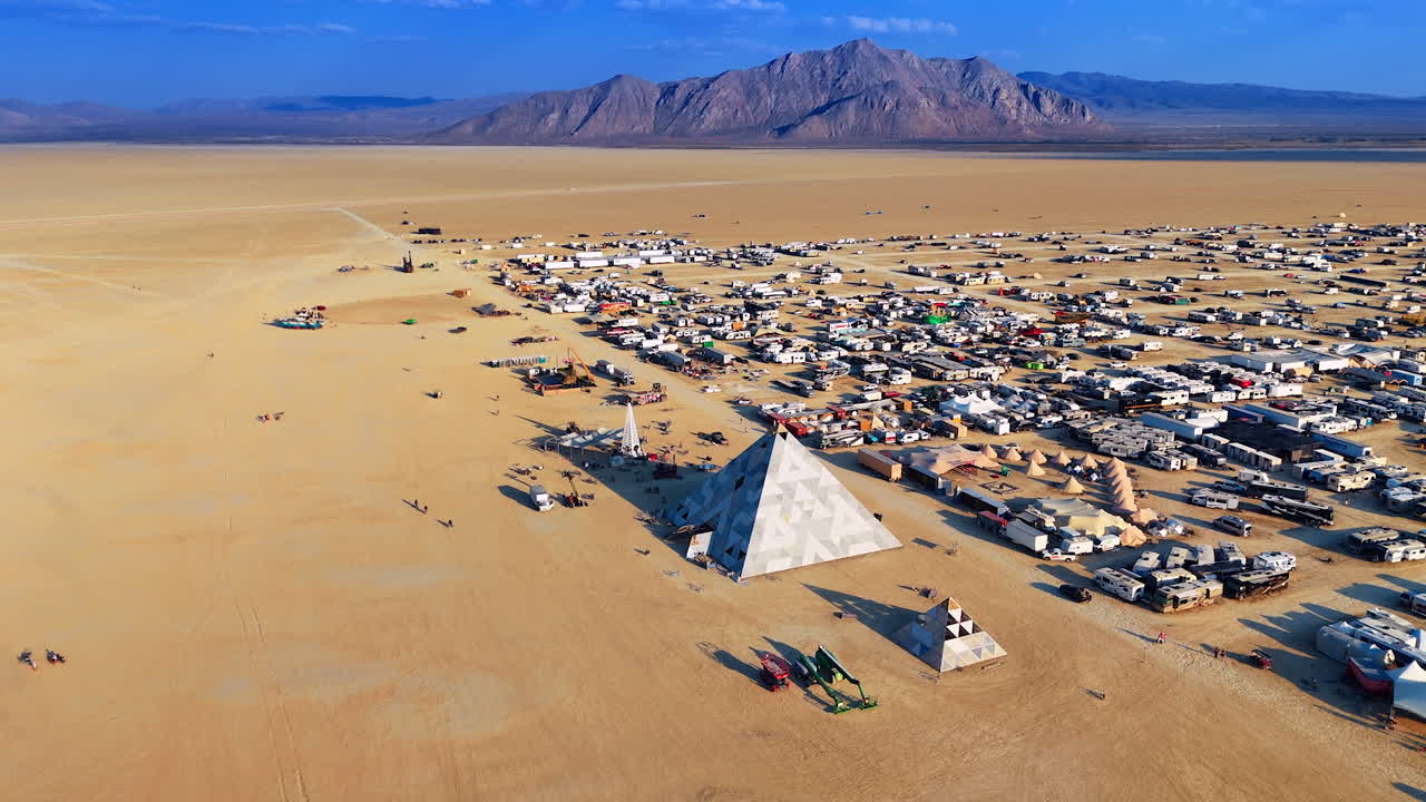 Nevada, USA, 22 August 2025: Burning Man camp with pyramid and mountains view. Wide aerial view of Burning Man desert camp with pyramid installation and distant mountains