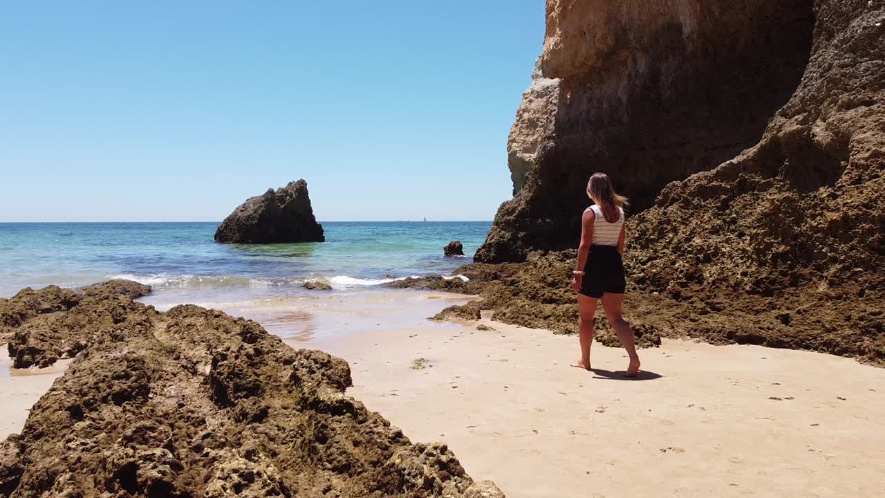 playa praia dos tres irmaos, algarve, portugal - niña camina por la playa de arena a través del mar azul claro