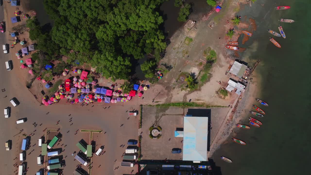 Wewak Sundaun fish Market Wewak Hill buildings cars traffic people boatsPapua New Guinea aerial drone downtown coastal town coastline beach Dogreto Bay sunny morning colorful umbrellas static