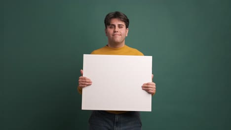 cheerful man showing blank banner in green studio