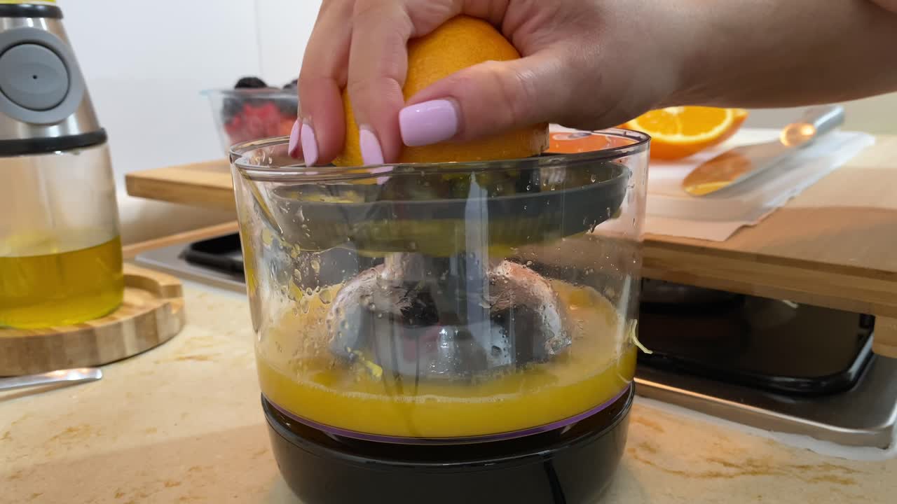 primer plano de la mano femenina exprimiendo naranja fresca usando exprimidor de jugo, desayuno saludable