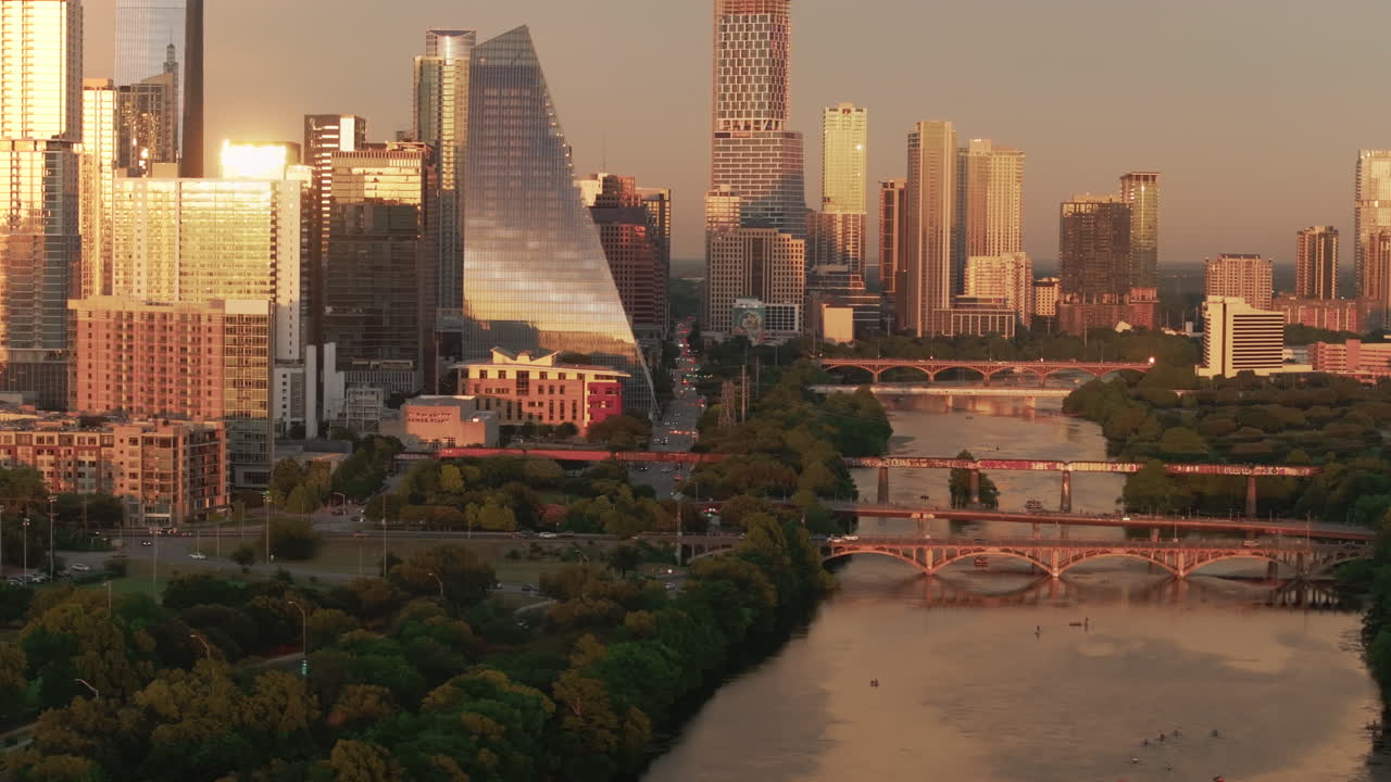 Drone captures the Austin, Texas skyline glowing as the golden hour sun reflects off downtown buildings. A cinematic, high-contrast sunset scene showcasing warm light and modern city architecture