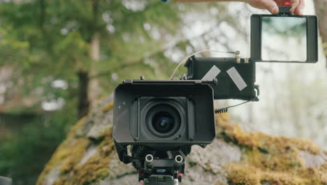 4x4 neutral density filter inserted into matte box by caucasian hands in woods