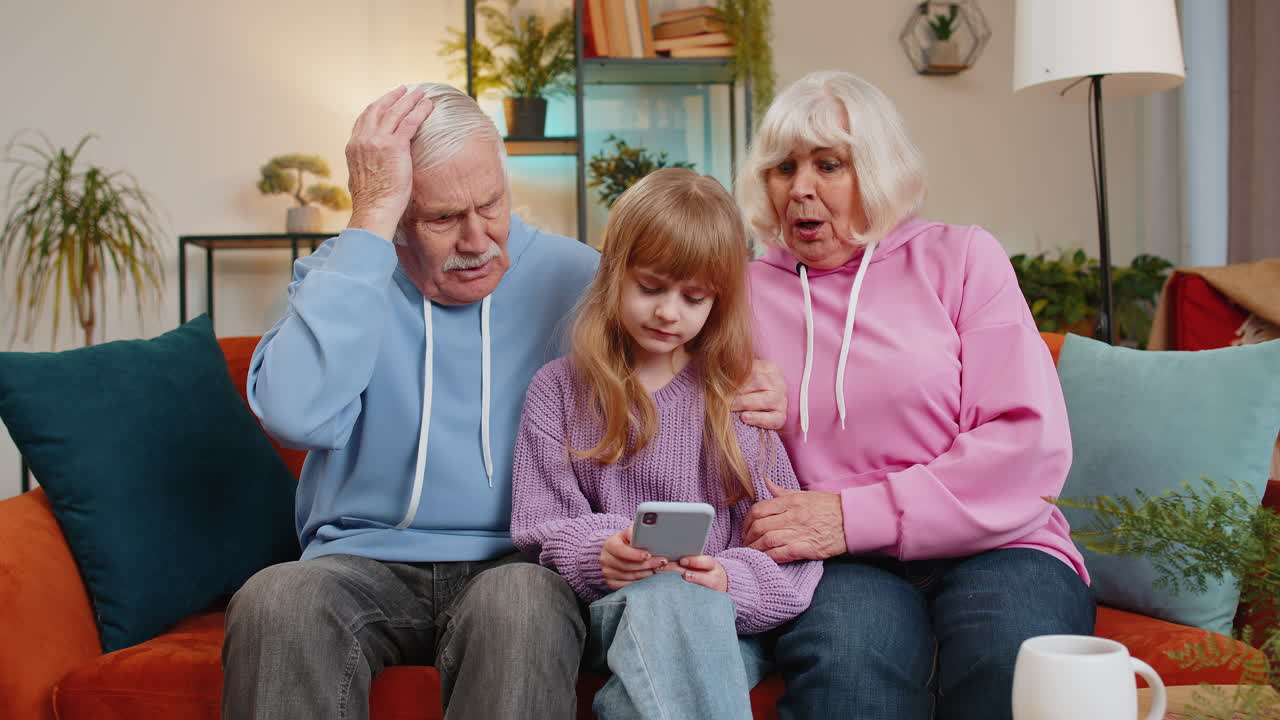 Child girl granddaughter grandfather grandmother playing game on smartphone losing fail at home