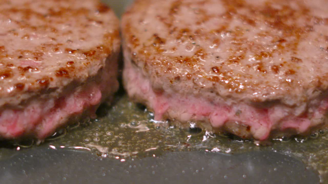 Moving Close Up Shot Across Aberdeen Angus Beef Burgers Cooking on High Heat with Fat Oozing from Middle. Tasty Hot Frying Food