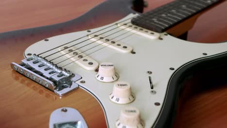 Slide-motion-of-old-electric-guitar-with-a-fine-pattern-of-guitar-strings-placed-on-a-wooden-floor-table