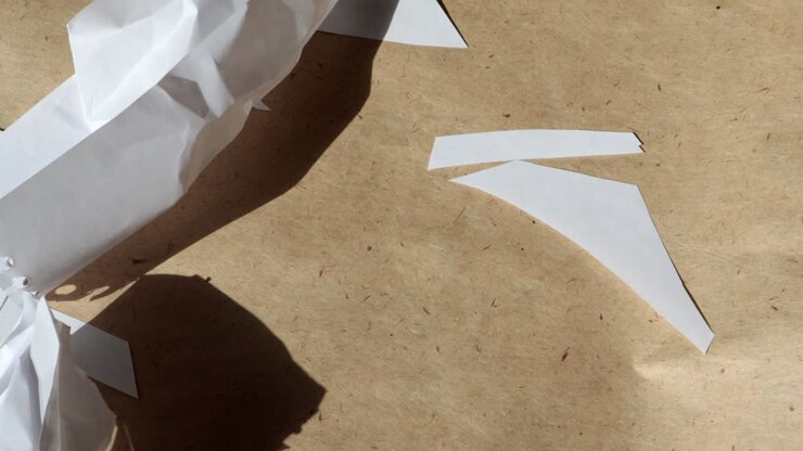 4k video, Macro photography of crumpled white sheets flying away from the wind on the background of brown kraft paper