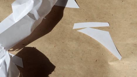 4k video, macro photography of crumpled white sheets flying away from the wind on the background of brown kraft paper