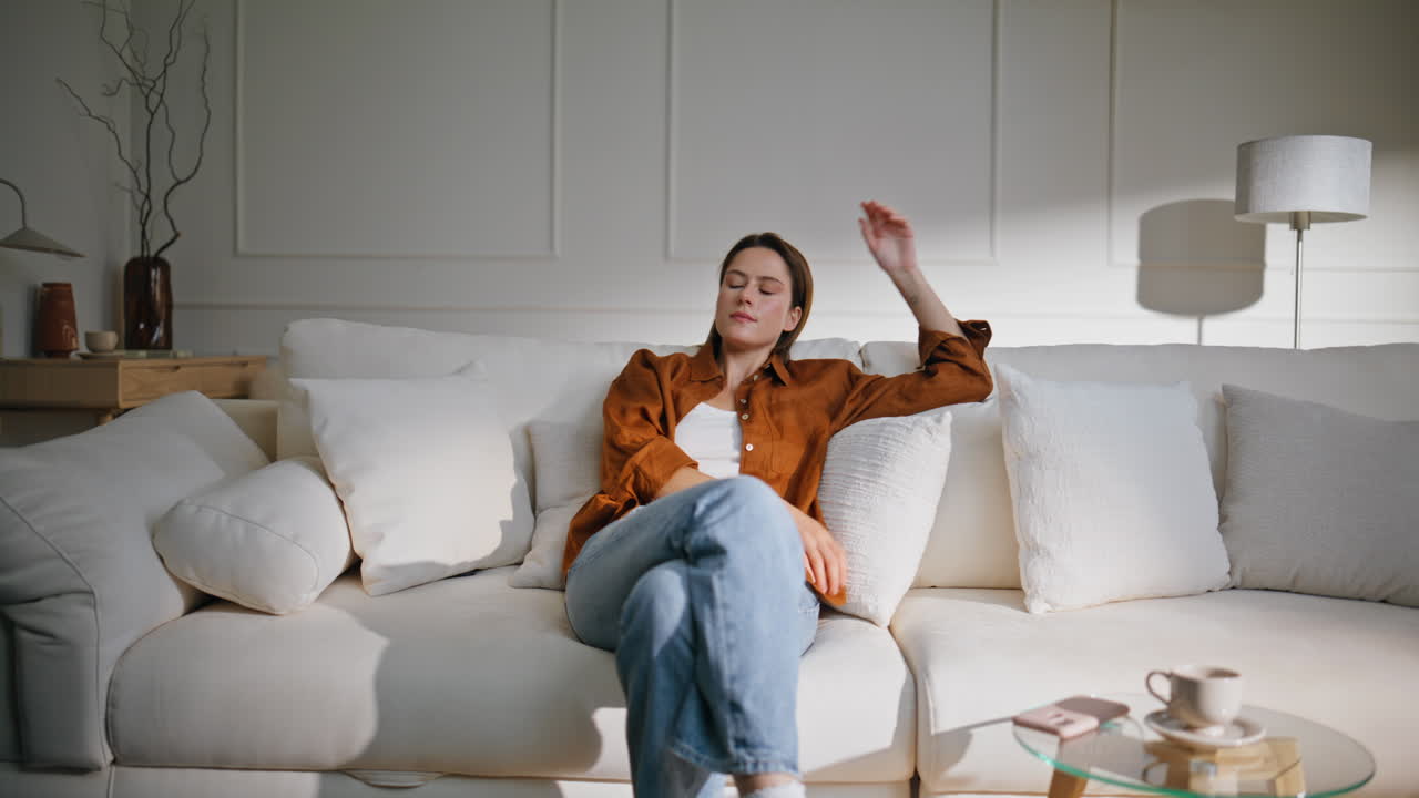 Tired woman sit sofa living room. Casual brunette falling on cozy home couch