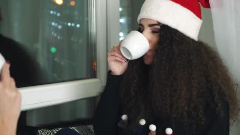 girls drinking cup of tea. young women wearing red hat and drinking cup of tea on window sill