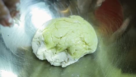 close up view of african american woman's hands kneading pizza dough in a silver pan in slow motion