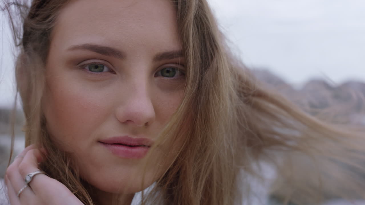 retrato de cerca de una mujer hermosa sonriendo disfrutando de la playa relajándose en la orilla del mar el viento soplando el cabello explorando un estilo de vida tranquilo y despreocupado